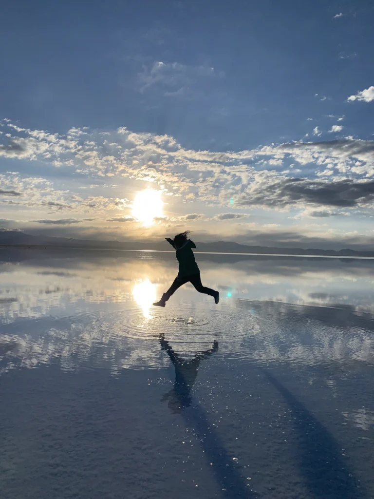 Traveler jumping over the mirror effect at Salar de Uyuni