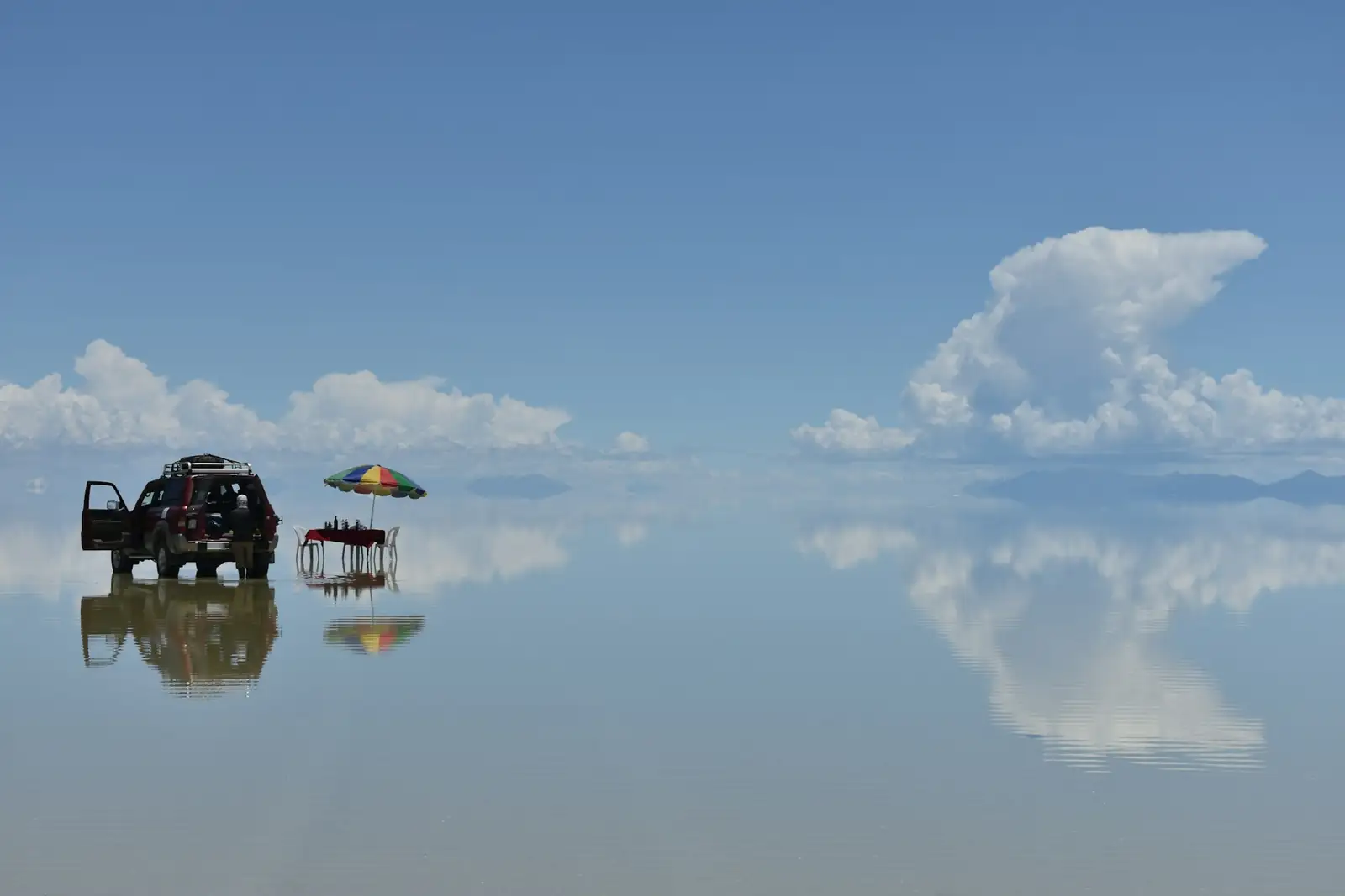 Picnic table and 4x4 on the flooded Salar de Uyuni in the rainy season