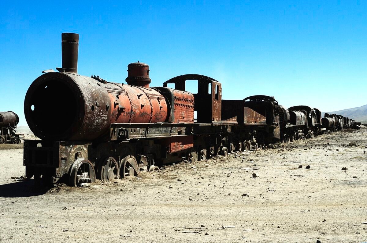 Rusted steam locomotive at the Uyuni train cemetery under a deep blue Altiplano sky